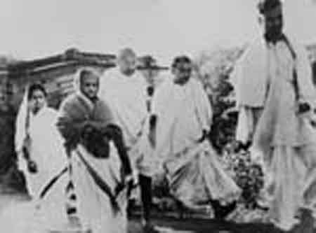Kasturba Gandhi being garlanded by a small girl while Gandhiji and others look at Sriniketan.jpg